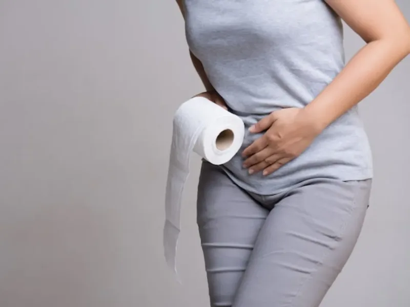 Woman holding a hand to her lower abdomen, a common way people describe bladder leakage discomfort