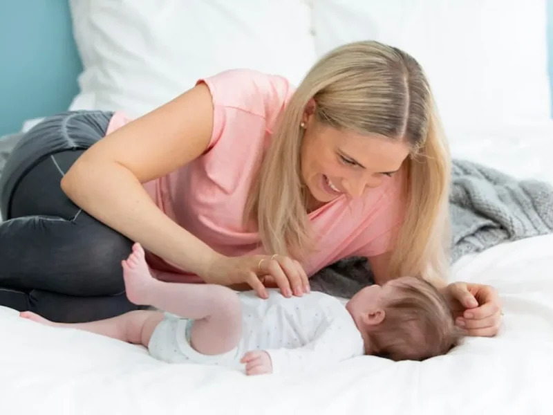 Mother leaning over her newborn baby lying on a bed