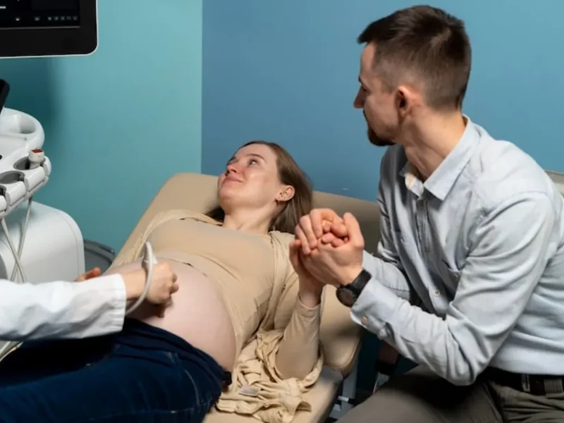 Pregnant woman holding her partner's hand during a prenatal ultrasound appointment